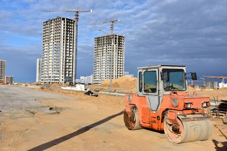 Paving roller machine during road work. Road roller at construction site for paving works. Screeding...
