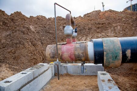 Laying heating pipes in a trench at construction site. Installation underground storm sewer pipes of...