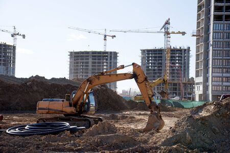 Excavator working at construction site on earthworks. Backhoe digs ground for the foundation and for...