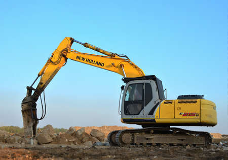 Minsk, Belarus 02.09.2019: Excavator New Holland E215B with hydraulic breaker hammer for the...