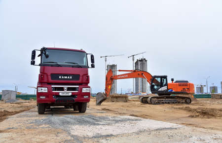 Minsk/Belarus, MAY 25, 2020: Red dump truck KAMAZ-65801-002-68(Ð¢5) 8Ñ4 and excavator HITACHI on construction siteのeditorial素材