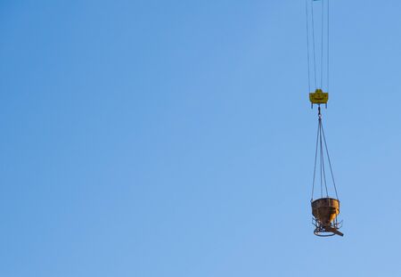 Tower crane lifting concrete bucket for pouring concrete during construction residential building on...