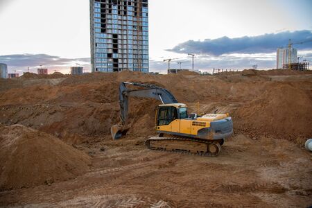 Excavator working at construction site on earthworks. Backhoe digs ground for laying concrete pipes....