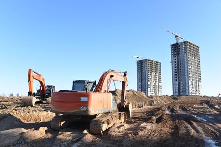 Excavator working at construction site on earthworks. Backhoe digging building foundation. Paving...