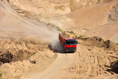 Dump truck transports sand in open pit mine. In the production of concrete, concrete for the construction using coarse sand. Quarry in which sand and gravel is excavated from ground. Mining industryの写真素材
