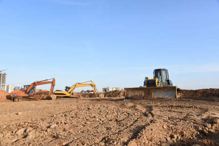 Excavators and dozer digs ground at a construction site for installing sewer storm pipes. Backhoe...