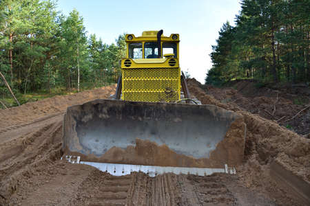 Dozer during clearing forest for construction new road. Yellow Bulldozer at forestry work...