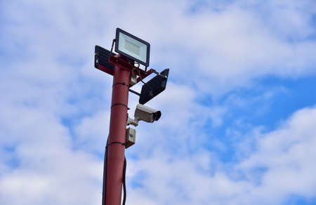 Video Surveillance. Video Camera on side post against a blue sky background. Security concept,...