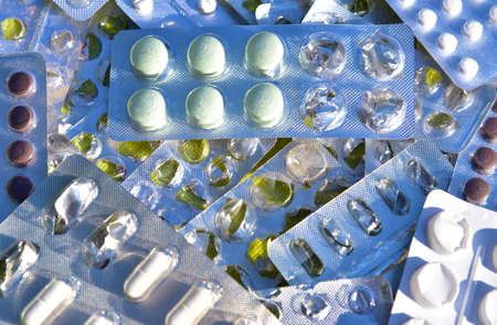Many colorful tablets and medicines drugs in plastic pharmaceutical packaging on the purple...