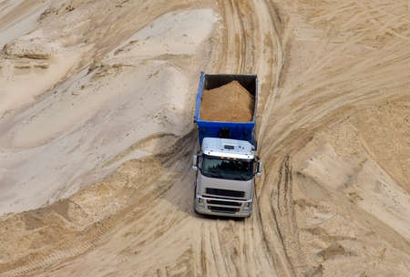 Truck with tipper semi trailer transported sand from the quarry. Dump truck working in open pit mine. Sand and gravel is excavated from ground. Mining industryの写真素材