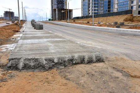 Road works activity at construction site. Construction and development projects on roads in city. Road concreting. Asphalt pavement is layered over concrete pavementの写真素材