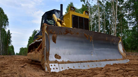 Dozer during clearing forest for construction new road. Yellow Bulldozer at forestry work...