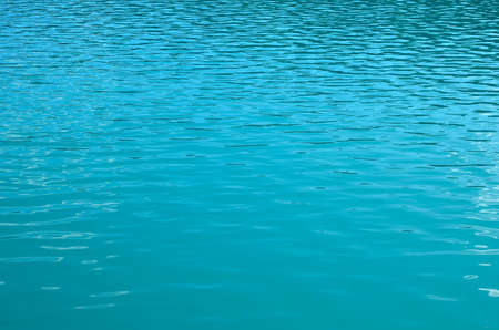 Turquoise clear ocean water background in summer tropical season. Transparent sea water texture with sunny reflections. Travel in paradiseの写真素材