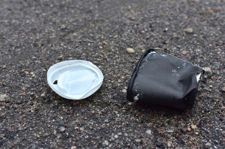 Crumpled a paper coffee cup on asphalt. Discarded disposable coffee cup with a plastic lid on road....