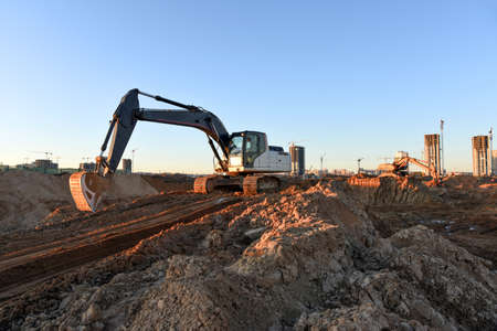 Excavators during earthworks at construction site. Backhoe the digging pit for construct building...