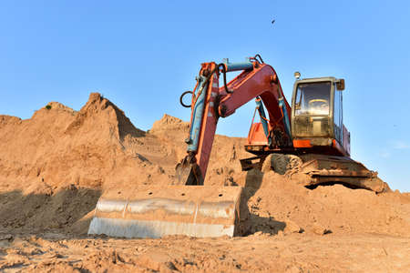 Bucket wheel excavator on earthmoving. Backhoe digs sand on blue sky background. Construction...