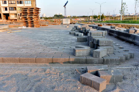 Installing paving bricks on patio at construction site. Laying paver slabs and brick, borders in the...