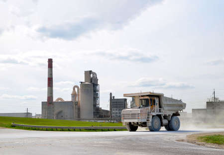Big yellow dump truck on the background of an industrial cement factory. Concrete factory. Loading...