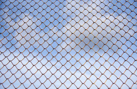 Fence with metal mesh on a background of blue skyの写真素材