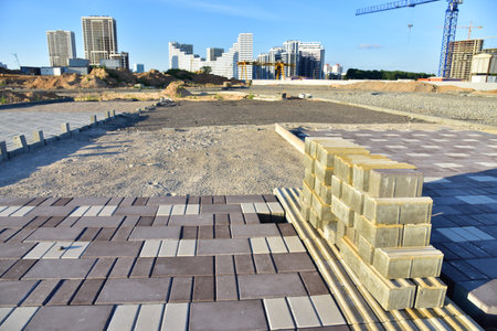 Process of installing paving bricks at construction site. Laying paving slabs and borders in town pedestrian zone. Screeding the sand for install concrete blocks. Road works on pavement renovationの写真素材