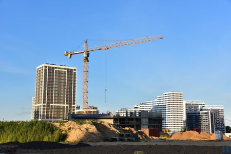 Tower crane working at construction site on blue sky background. Construction process of the new...