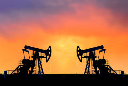 Crude oil pump jack at oilfield on atmospheric sunset backround. Fossil crude output and fuels oil production. Oil drill rig and drilling derrick. Global crude oil Prices, energy, petroleum demandの写真素材