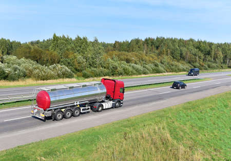 Tank truck transport of liquid, foodstuff. Metal chrome cistern tanker for food transportation on highway. Out of focus, possible granularity.の写真素材
