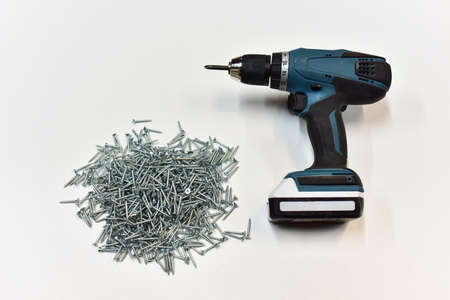 Cordless combi drill for used as normal drill, impact drill and screw driver. Cordless impact screwdriver and self-tapping screws for wood on white wooden table. Brushless battery drillの写真素材