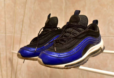 Sneakers to dry in the bathroom after washing. A pair shoes dry after wash. Footwear on heated towel...