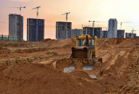 Dozer on earthmoving at construction site on sunset background. Construction machinery and equipment...