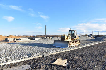 Bulldozer moves gravel during on road work at construction site. Dozer leveling stones for laying...