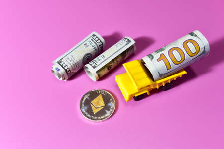 Ethereum Crypto coin and dollars on a pink background. One hundred dollar bills in the back of a toy dump truck and. Blockchain and financial technology. Transactions and market trading price chartの写真素材