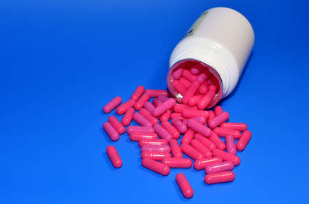 Pills from a bottle on blue background. Assorted pharmaceutical pills, medical tablets and capsules....