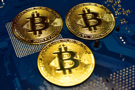 Bitcoin crypto coins on computer motherboard. BTC mining cryptocurrency and investing concept....