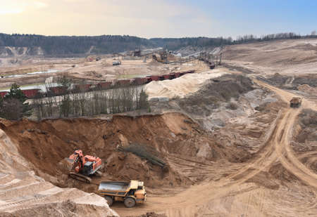 Excavator load sand in heavy mining truck at open-pit. Heavy machinery working in mining quarry....
