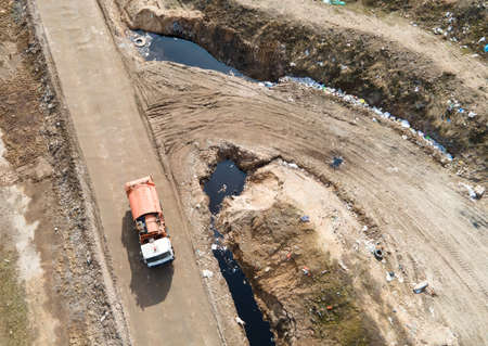 View from a drone to a garbage truck on a landfill with waste