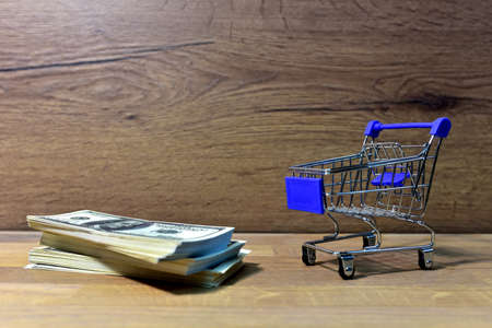 Supermarket Trolley and american dollars. Bundle Hundred Dollar Bills near shopping cart for buying...