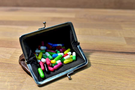 Pills in wallet on wooden background. Multicolored pharmaceutical pills, medical tablets and...