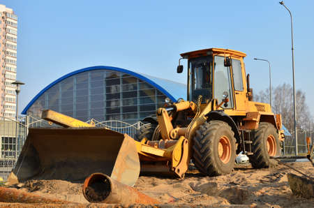 Wheel loader with a bucket on a street in the city during the construction of the road. Construction...