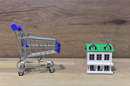 House and Supermarket Trolley. Home buying or selling. Building on credit housing or renting an apartment. Home in shopping cart for family. Real Estate Investing and Housing Market. American dreamの写真素材