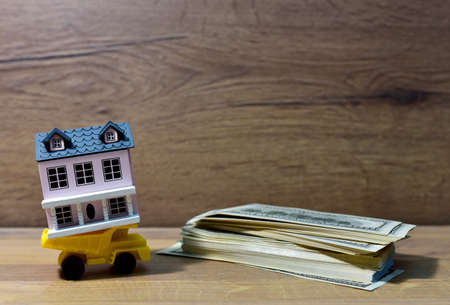 Miniature dump truck delivers a miniature family home at american dollars. Building on credit housing or renting an apartment. Home with Hundred Dollar Bills. Real Estate Investing and Housing Marketの写真素材