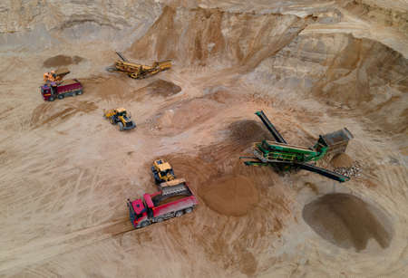 Wheel loader loading sand into dump truck in open pit. Arial view of jaw crusher sand making...