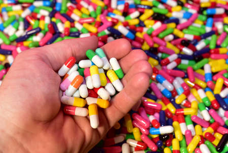 Multicolored pills in capsules in hand. Pharmaceutical pill for medical. Medical pill for...