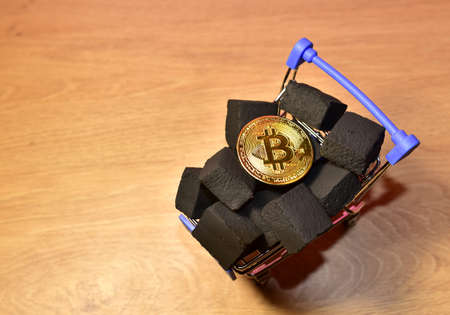 Bitcoin coin on black coal background in shopping cart. Cryptocurrency trading, BTC mining and investing concept. Blockchain and financial technology. Crypto prices and chartsの写真素材