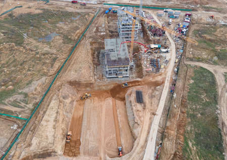 Tower cranes in action at construction site. Crane during formworks. Soil Compactor leveling ground...