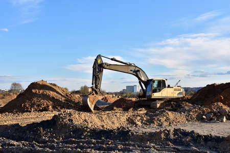 Excavator on earthworks at construction site. Backhoe on earthmoving and foundation work. Heavy machinery and equipment.の写真素材