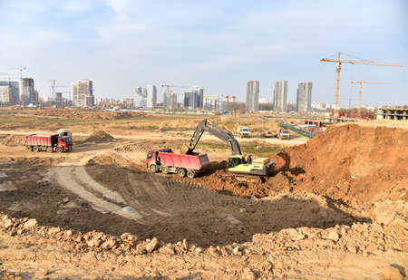 Excavator load the ground into dump truck on construction site. Developing the foundation for the...