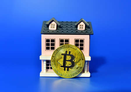 Bitcoin coin on the background of a wooden house. The concept of buying real estate and housing for cryptocurrency. BTC Crypto mining and investing. Blockchain and financial technology. Market capitalの写真素材
