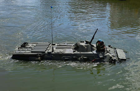 Sailing on BTR APC Amphibious Armored Personnel Carrier. Armed forces on military exercises in river. Military equipment and military armed tanks.の写真素材