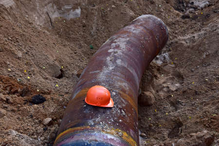 Safety helmet on a pipe in a trench during the construction of pipeline. Savior Tough Hat during workers' strike. Natural Gas and Crude oil. Petrochemical or sewage pipeの写真素材